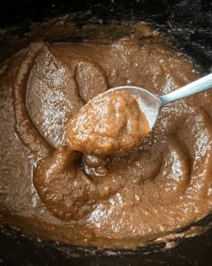 close up shot of cooked apple butter in a black slow cooker