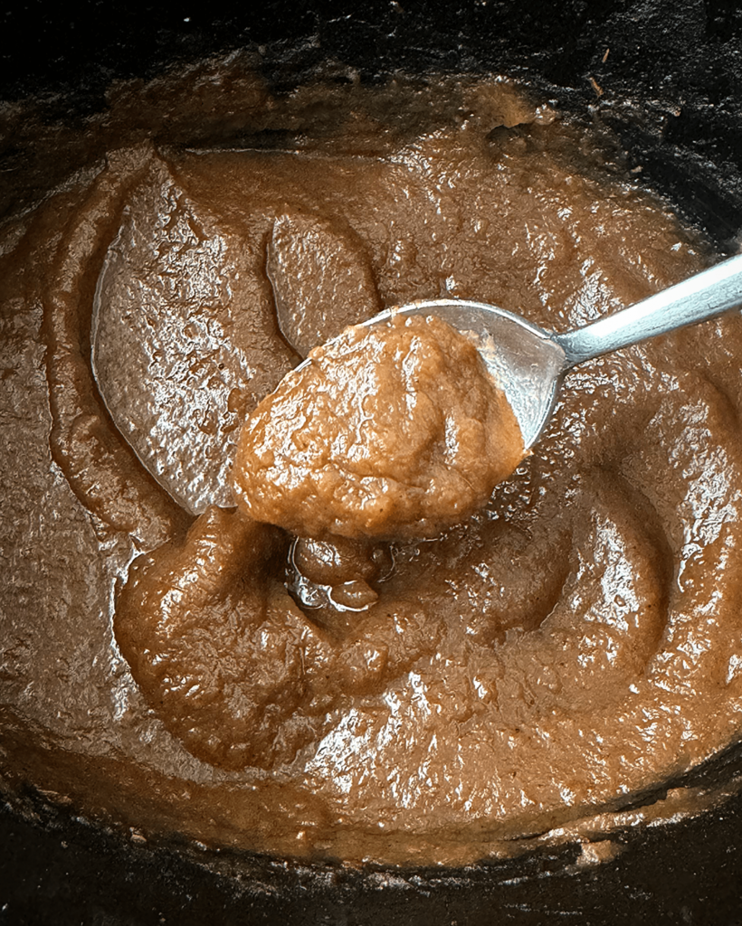 close up shot of cooked apple butter in a black slow cooker