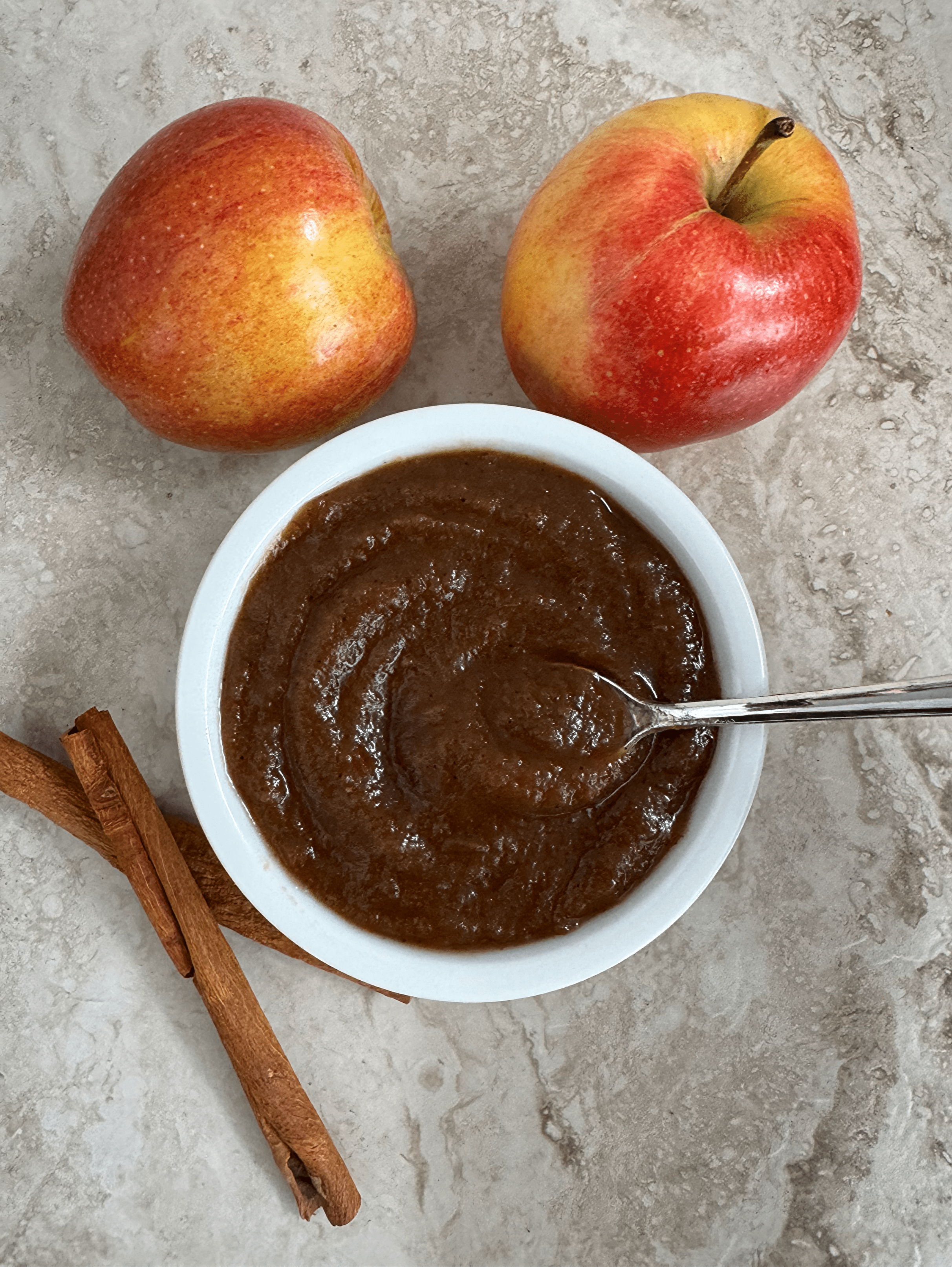 overhead shot of apple butter in a white bowl with a silver spoon