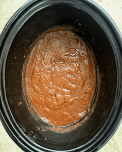 overhead shot of cooked apple butter in a black slow cooker