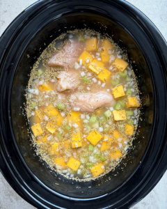 overhead shot of uncooked Crockpot Chicken Butternut Squash Soup in a black slow cooker