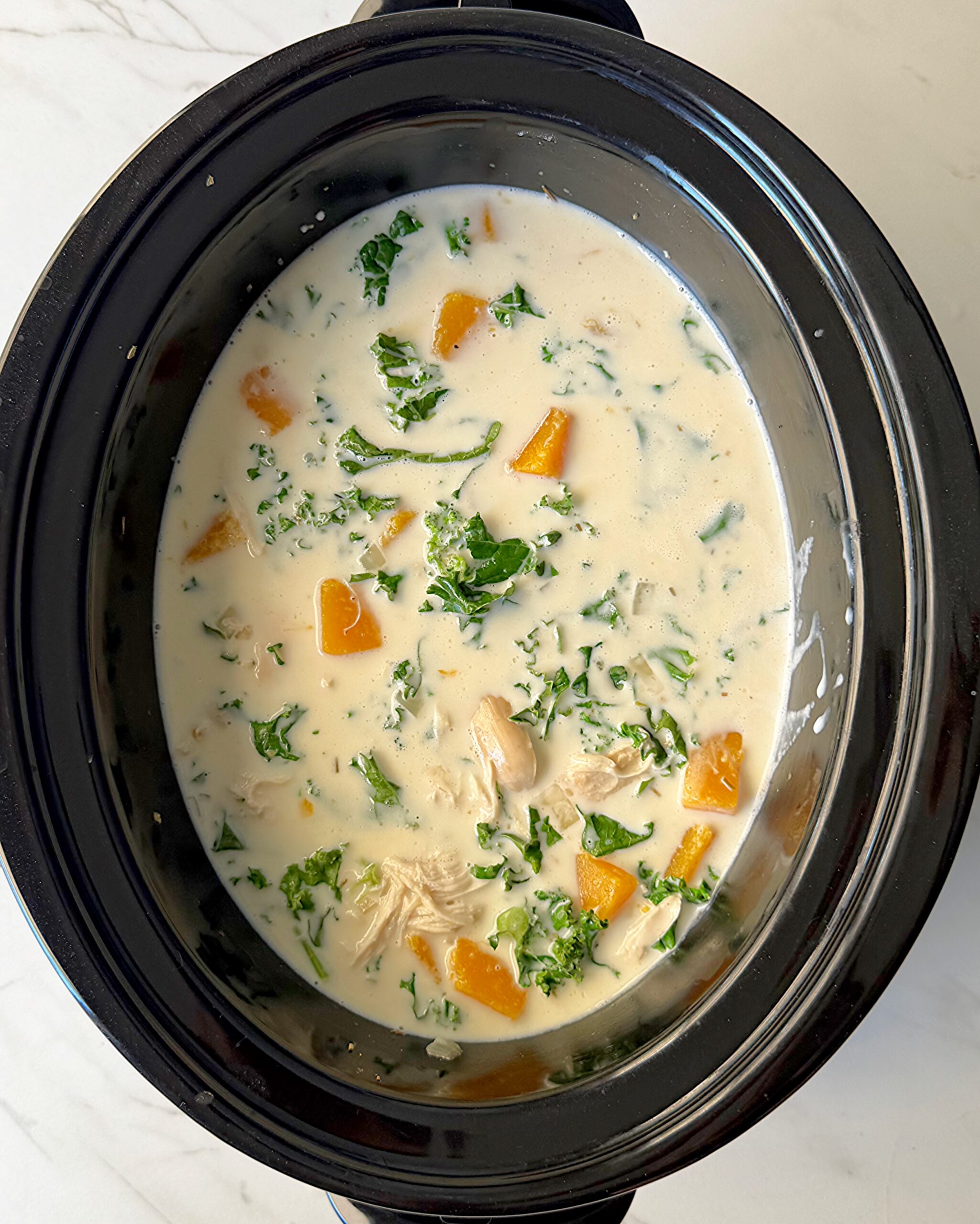 overhead shot of Chicken Butternut Squash Soup in a black slow cooker