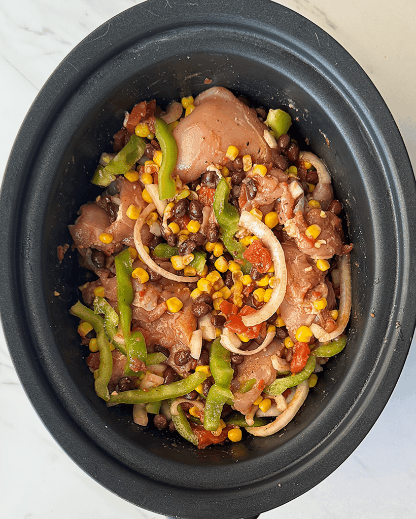 overhead shot of uncooked Santa Fe Chicken in a black crockpot