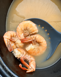 close up, overhead shot of cooked peel and eat shrimp in a black slow cooker