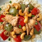 overhead shot of cooked Slow Cooker Cashew Chicken in a white plate garnished with sesame seeds