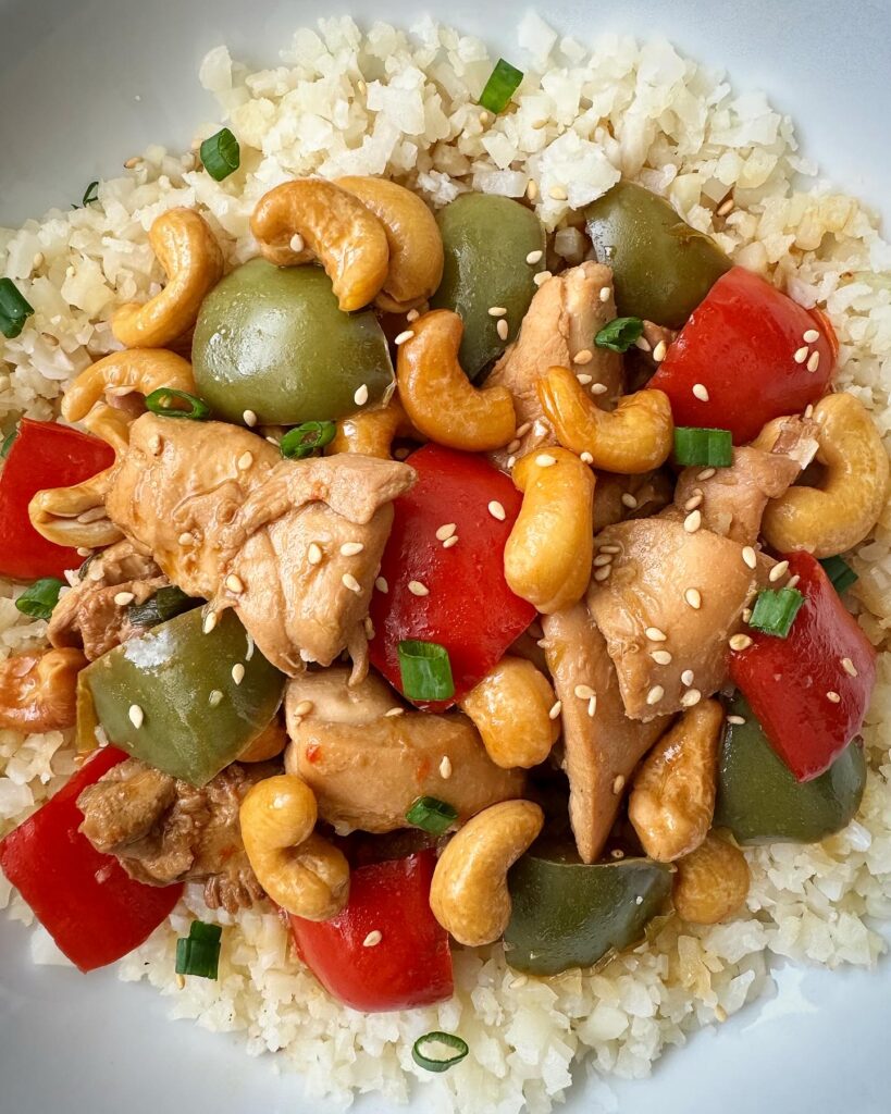 overhead shot of cooked Slow Cooker Cashew Chicken in a white plate garnished with sesame seeds