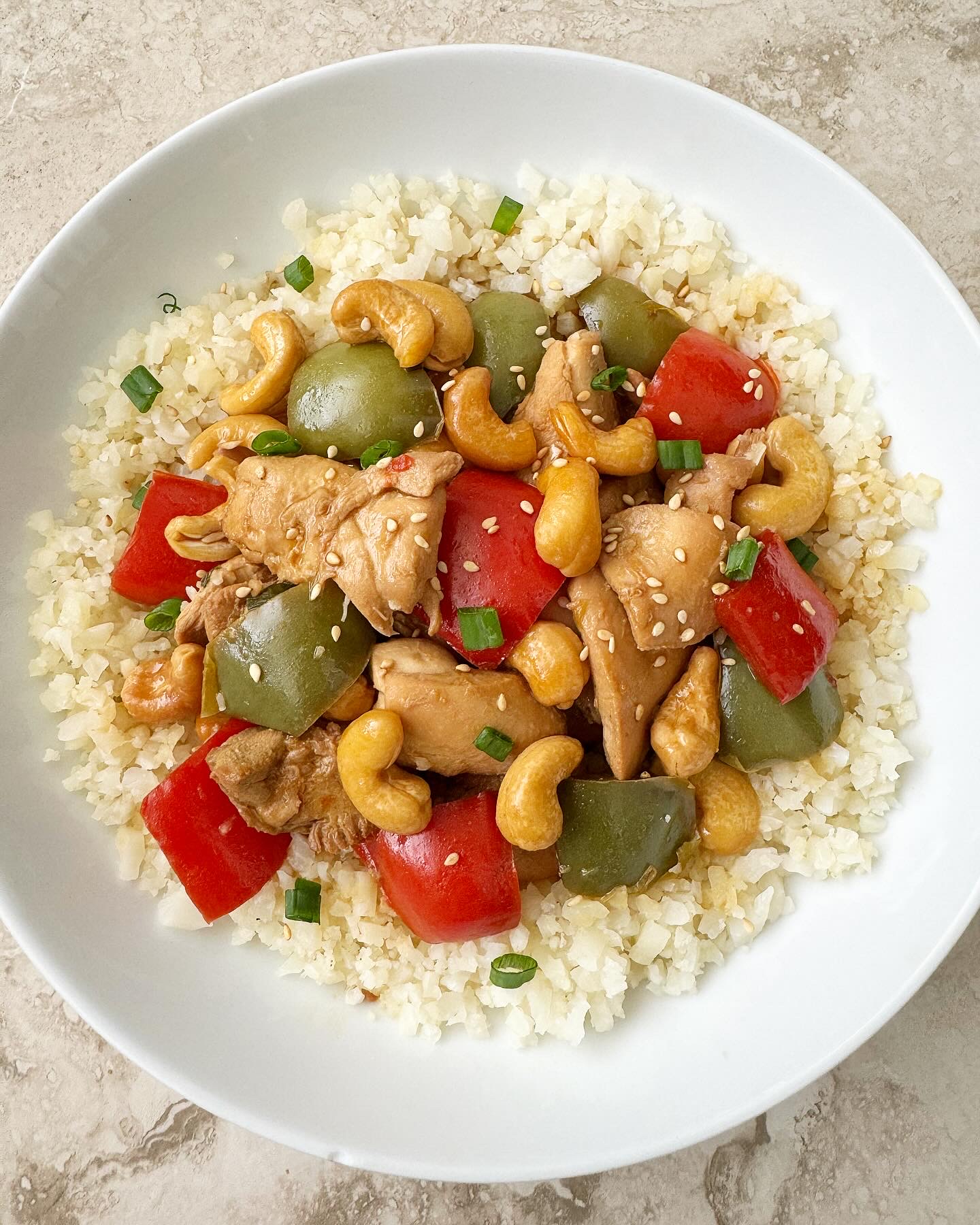 overhead shot of cooked Slow Cooker Cashew Chicken in a white plate garnished with sesame seeds