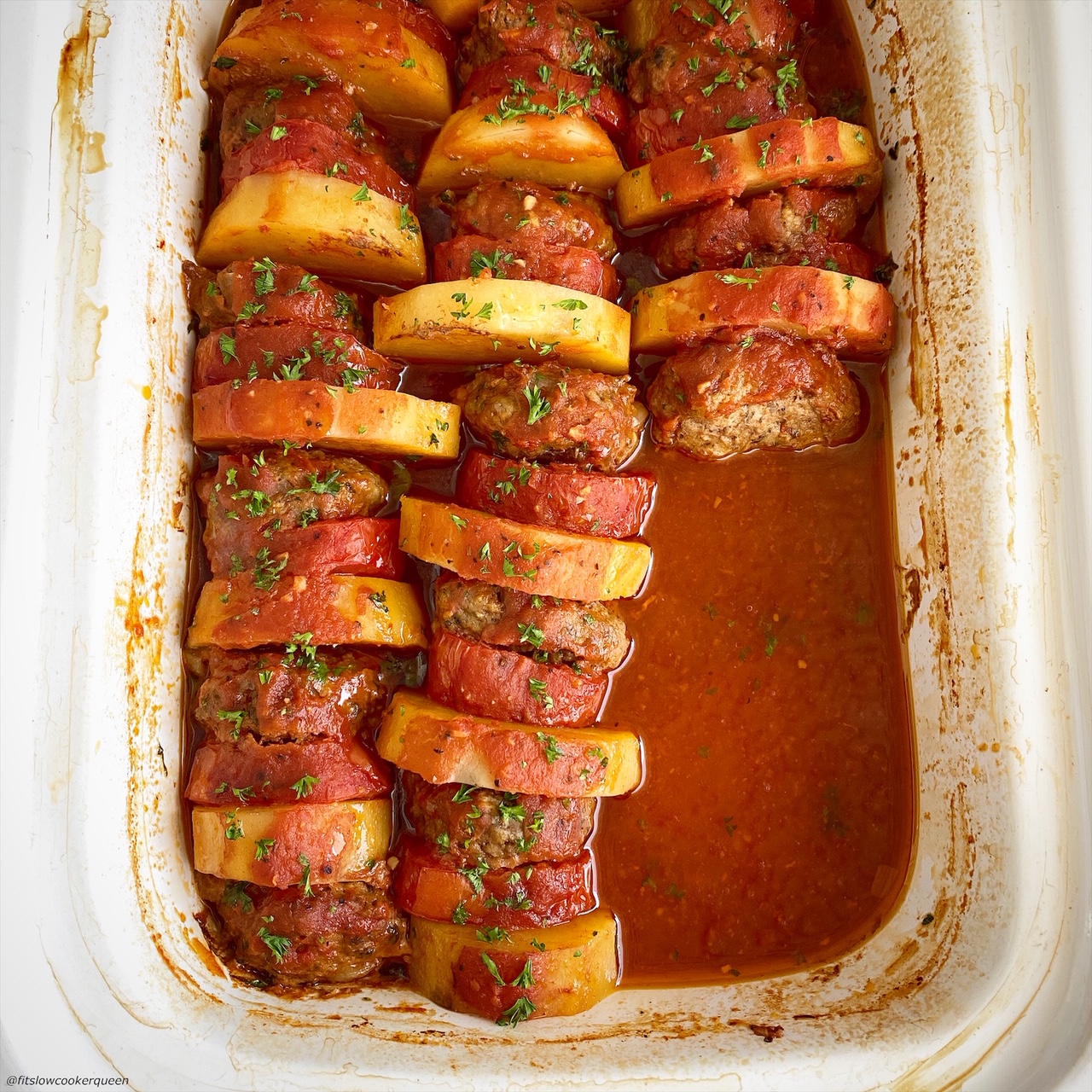 layered, cooked kofta patties, potatoes, and tomatoes in the slow cooker with tomato sauce on top & row of kofta missing