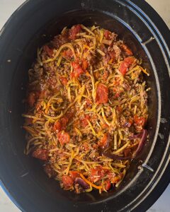 overhead shot of cooked slawghetti in a black slow cooker