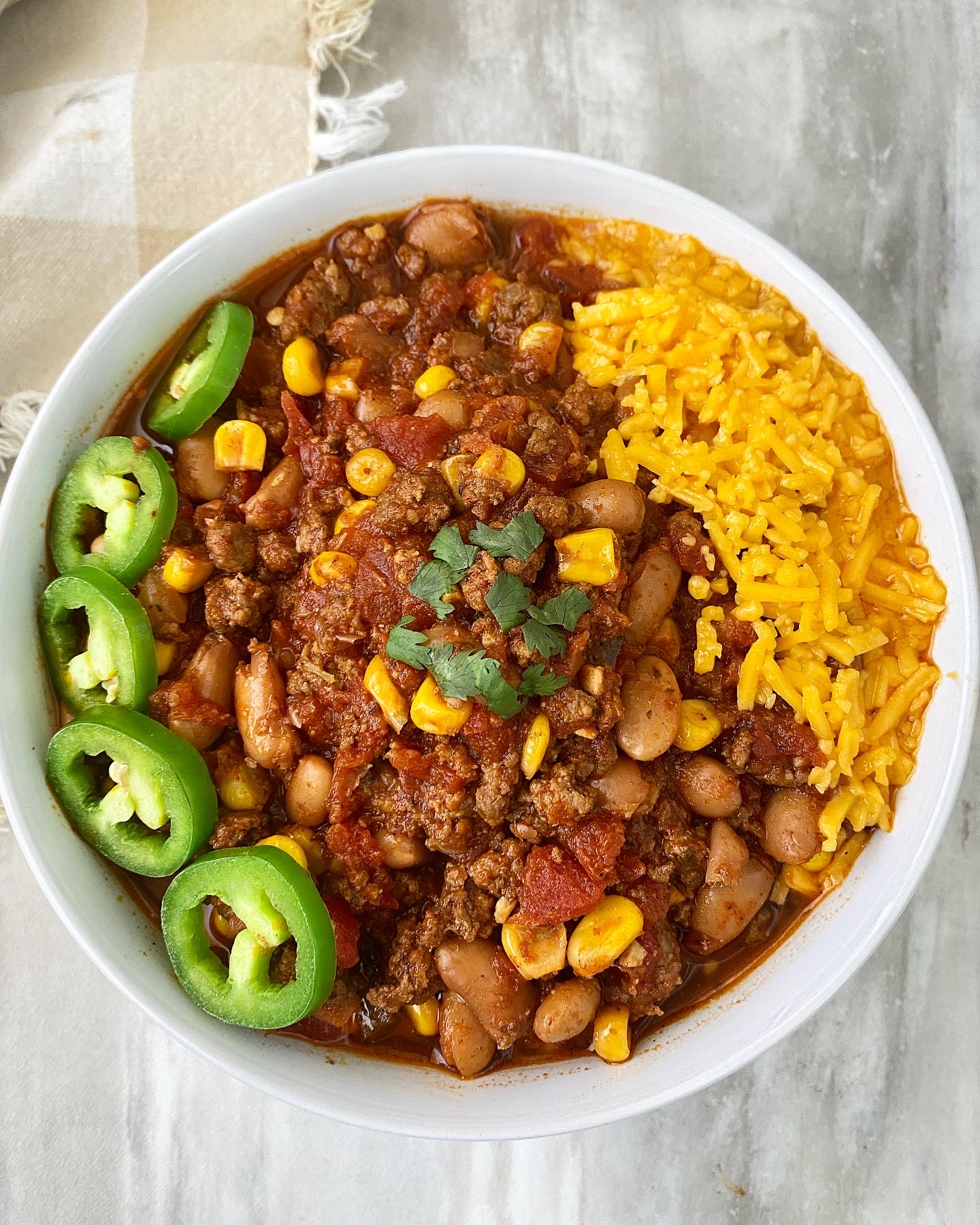 overhead shot of taco chili in a white bowl with a jalapeno with cheese