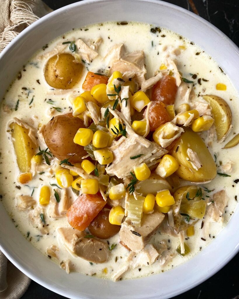overhead shot of turkey corn chowder in a white bowl garnished with fresh thyme