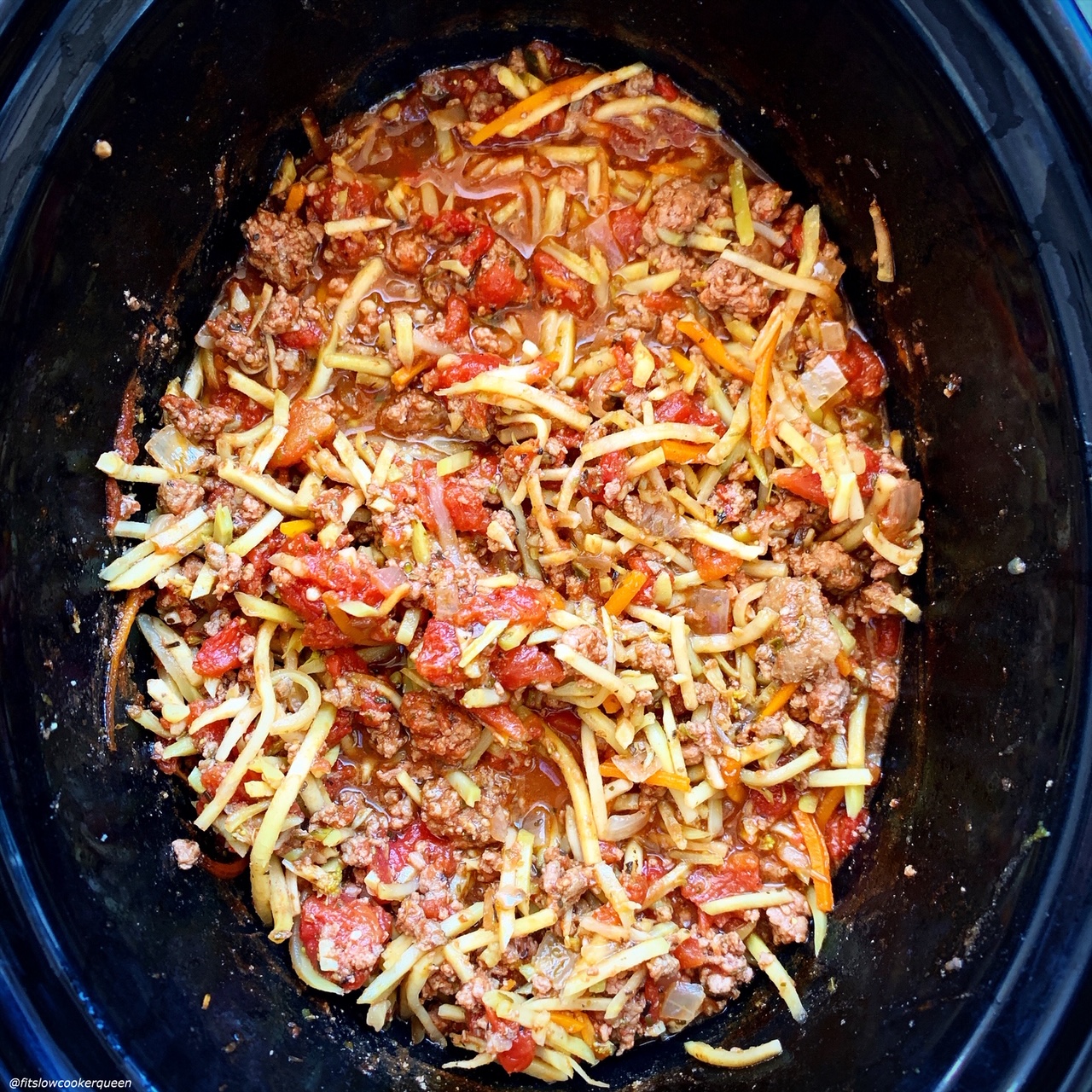 overhead shot of cooked slawghetti in a black slow cooker