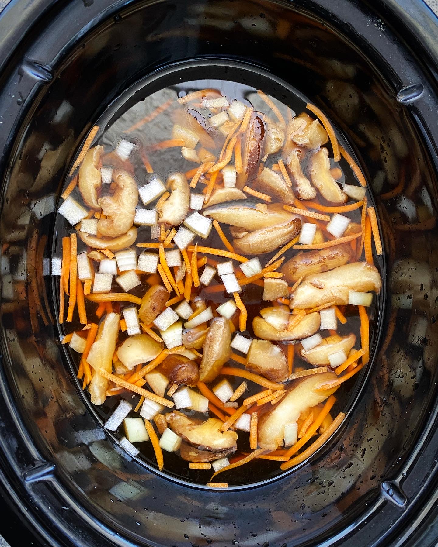 overhead shot of uncooked soup in a black slow cooker