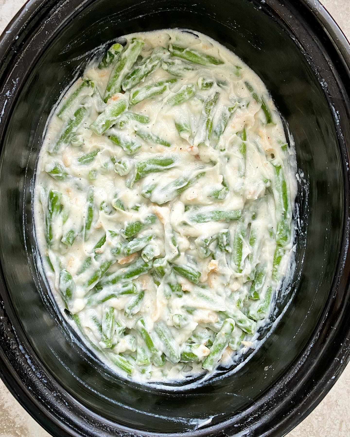 overhead shot of uncooked healthy green bean casserole in a black slow cooker