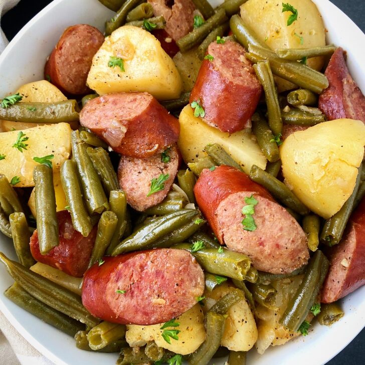 overhead shot of cooked Crockpot Sausage, Potatoes Green Beans in a white bowl