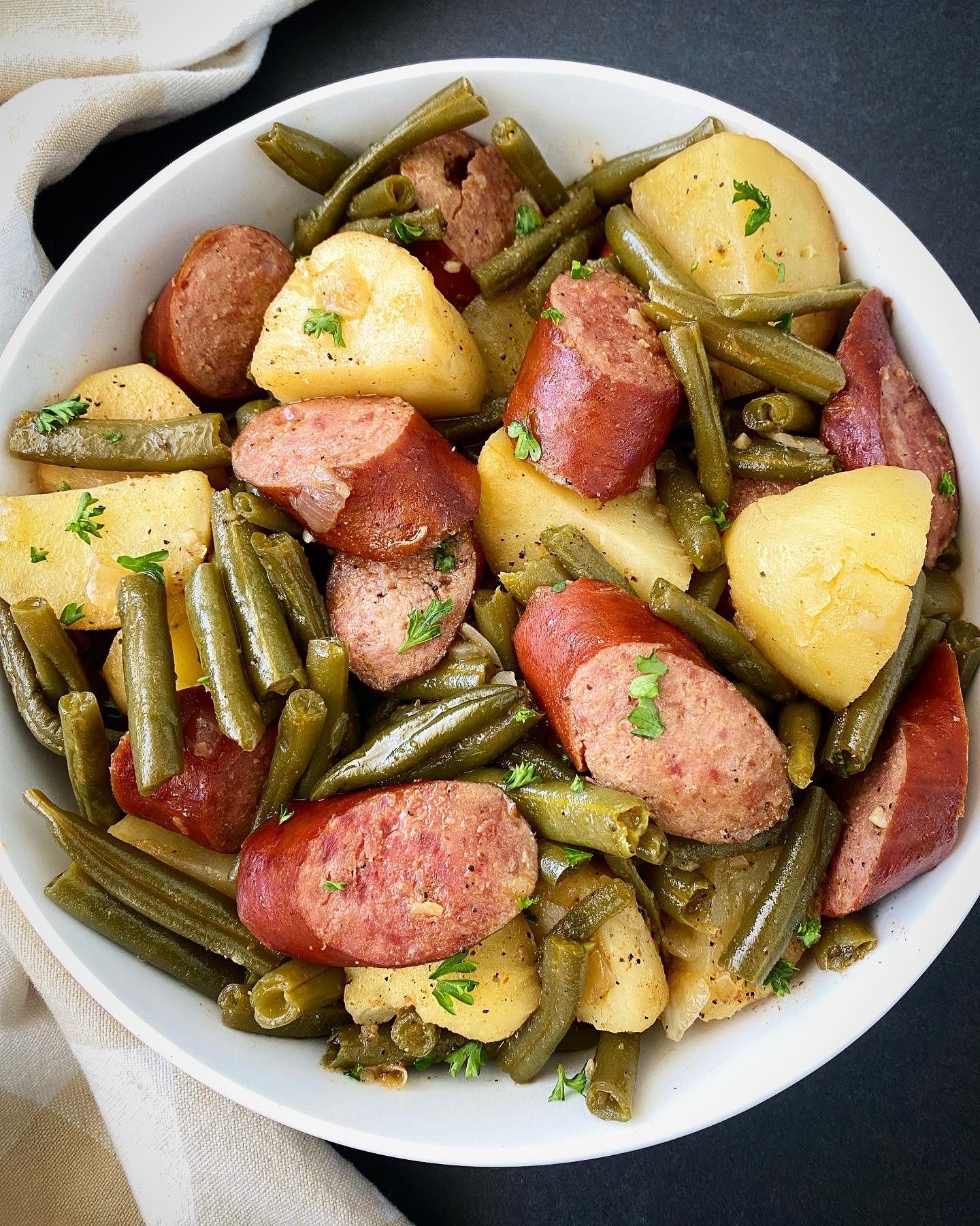 overhead shot of cooked Crockpot Sausage, Potatoes Green Beans in a white bowl