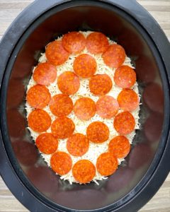 before pic of raw pizza chicken in the slow cooker with pepperoni on top