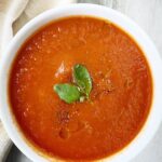 overhead shot of cooked roasted tomato soup in a white bowl