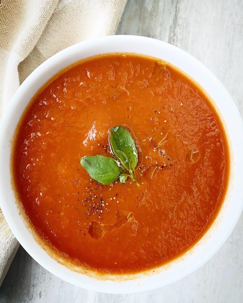 overhead shot of cooked roasted tomato soup in a white bowl