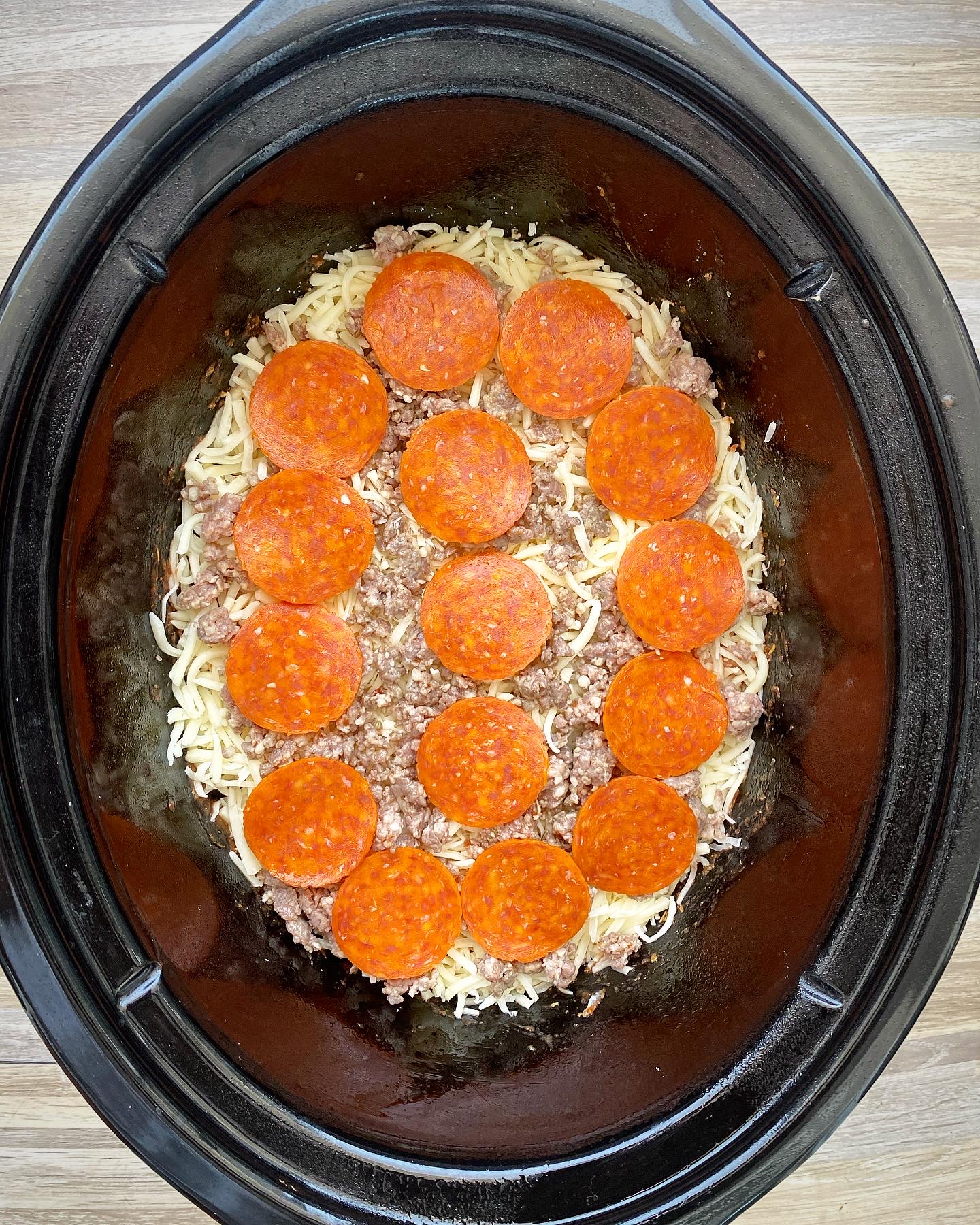 overhead shot of uncooked pizza chicken in a black slow cooker
