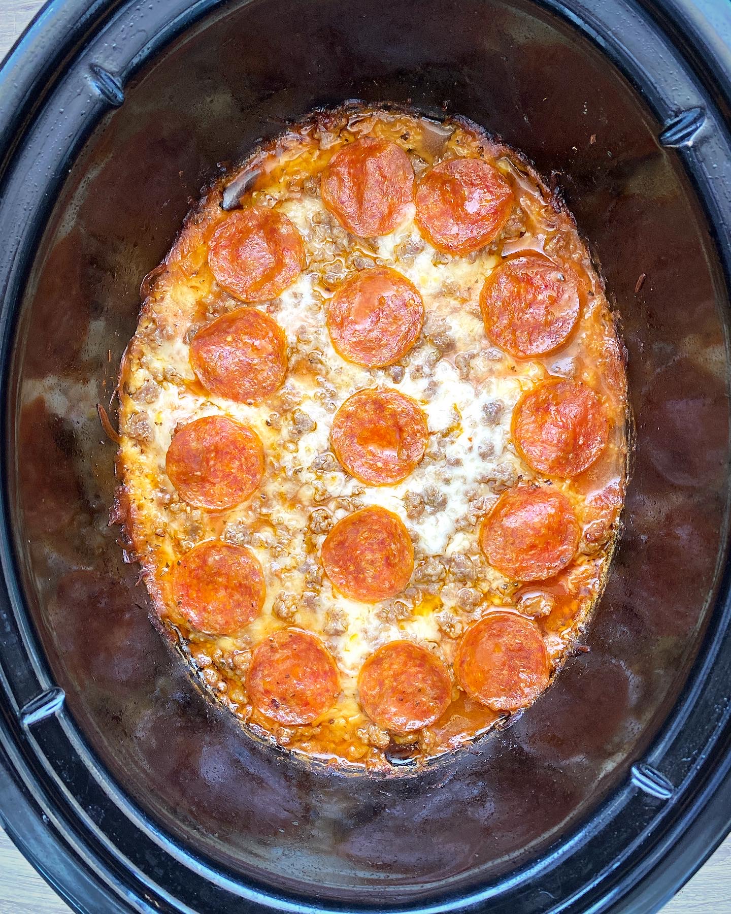 overhead shot of cooked pizza chicken in a black slow cooker