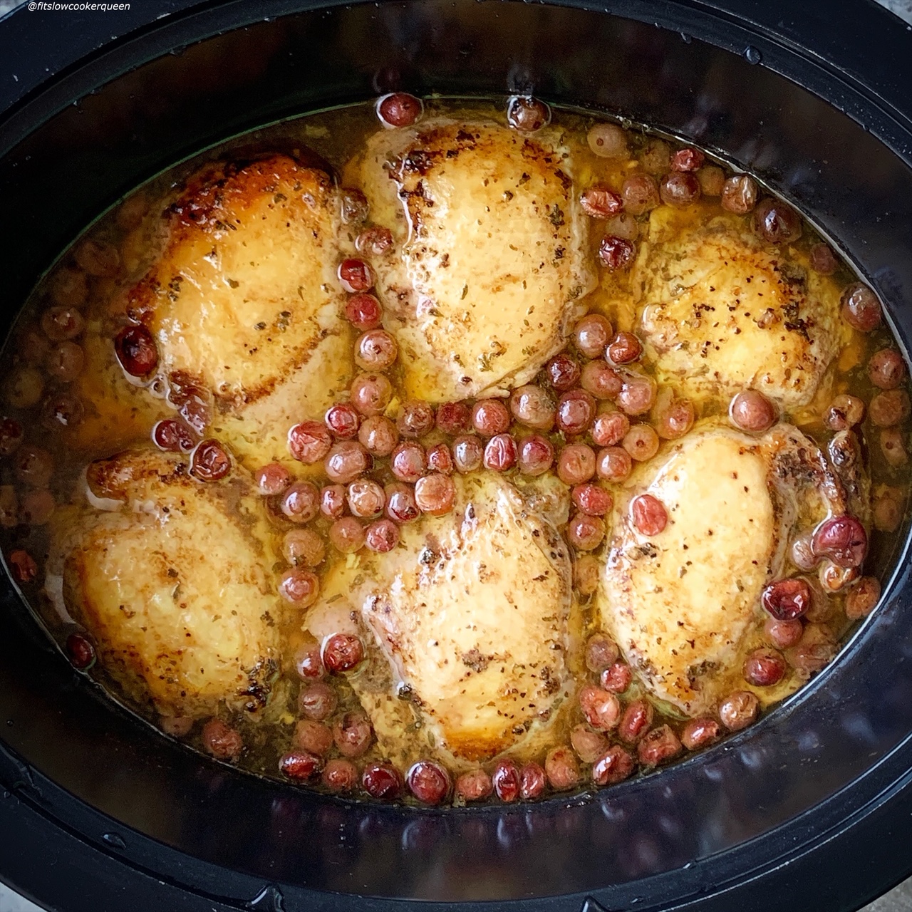 overhead shot of cooked balsamic cranberry chicken in a black slow cooker