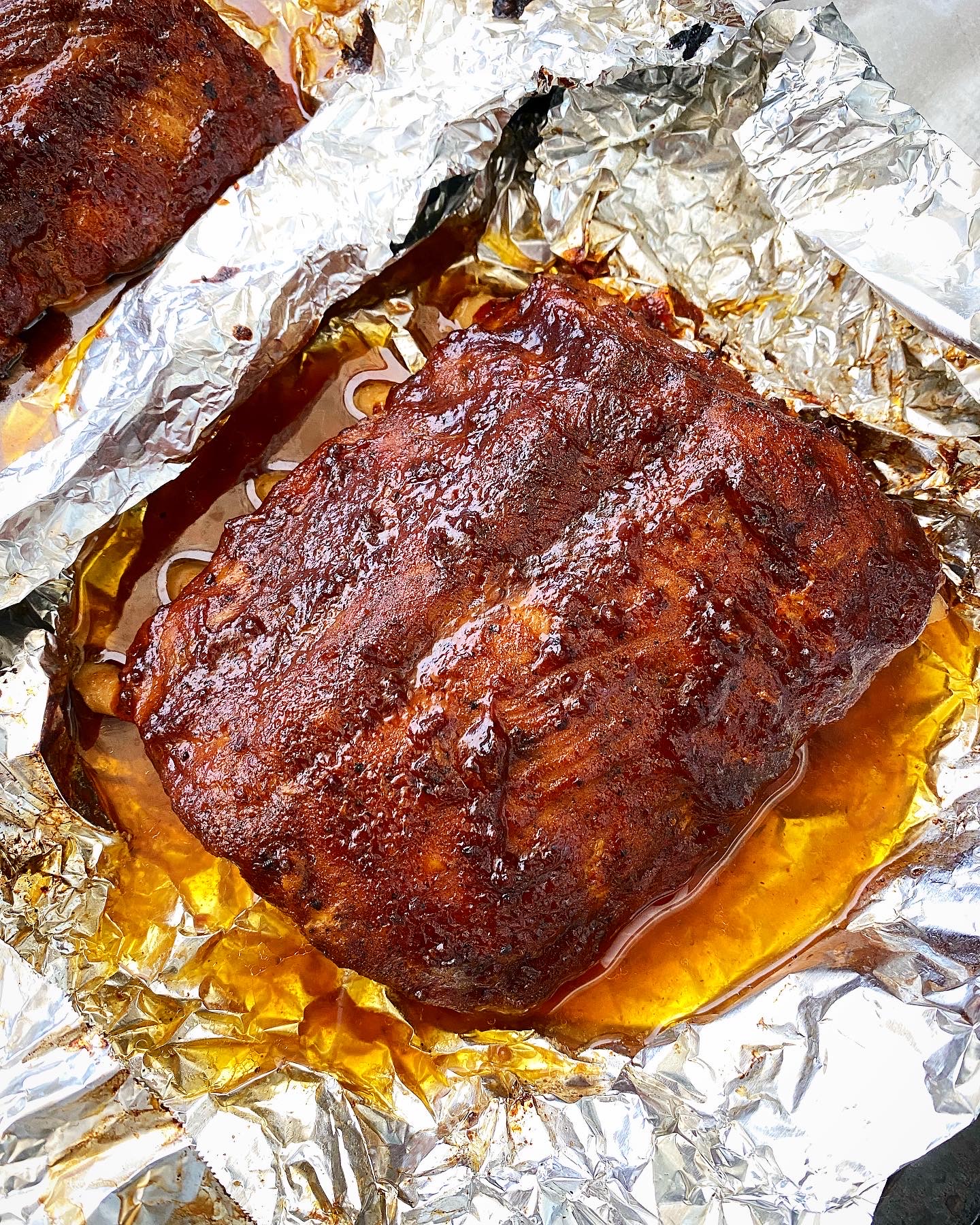 close up of broiled ribs with bbq sauce on foil