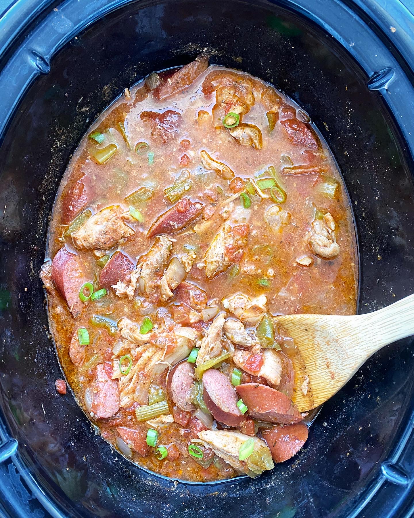overhead shot of cooked Cajun chicken & sausage in a black slow cooker
