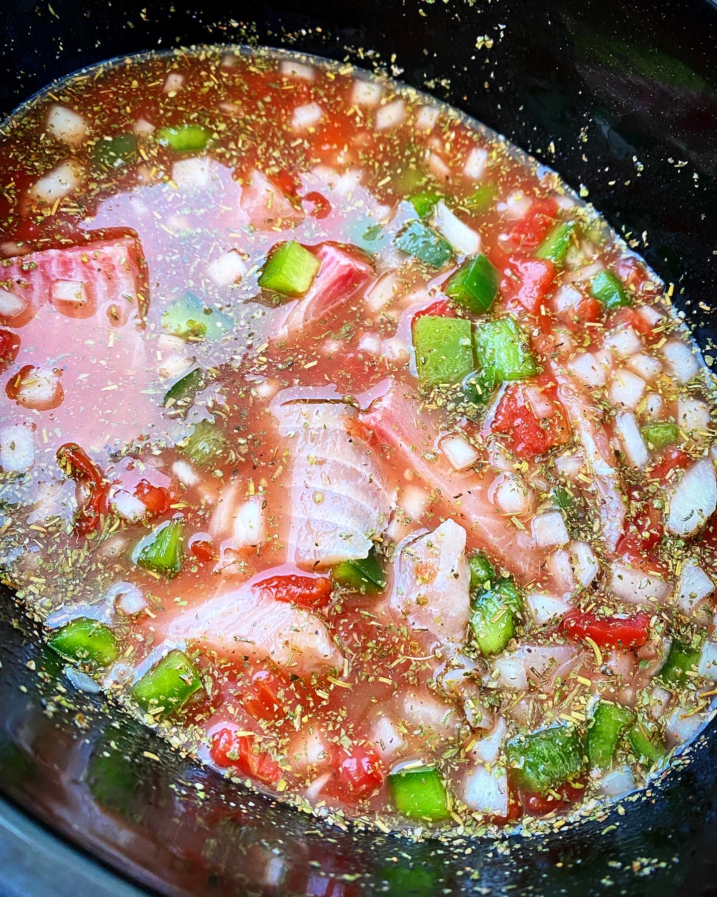 overhead shot of uncooked Slow Cooker Mediterranean Fish Stew in a black slow cooker