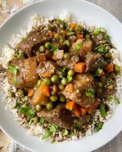 closeup overhead shot of cilantro beef stew in a white bowl garnished with fresh cilantro