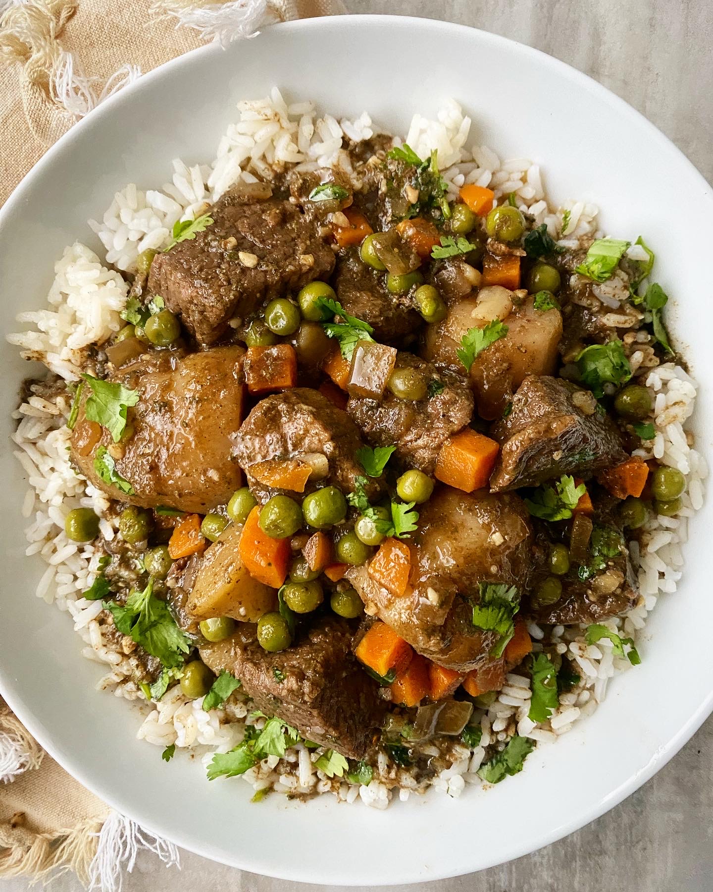 closeup overhead shot of cilantro beef stew in a white bowl garnished with fresh cilantro