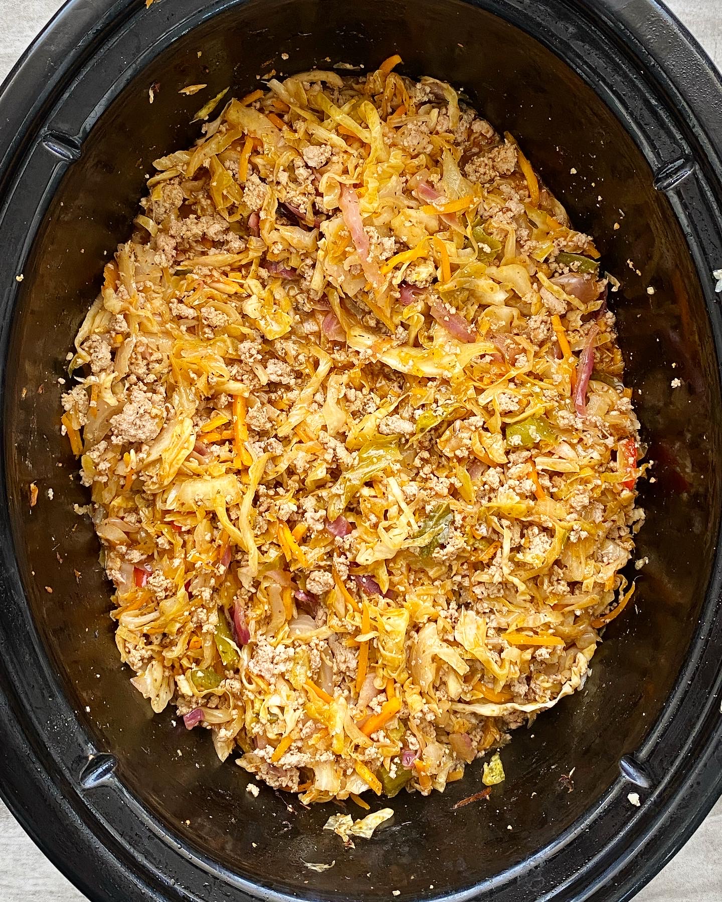 overhead shot of cooked spicy turkey slaw in a black slow cooker