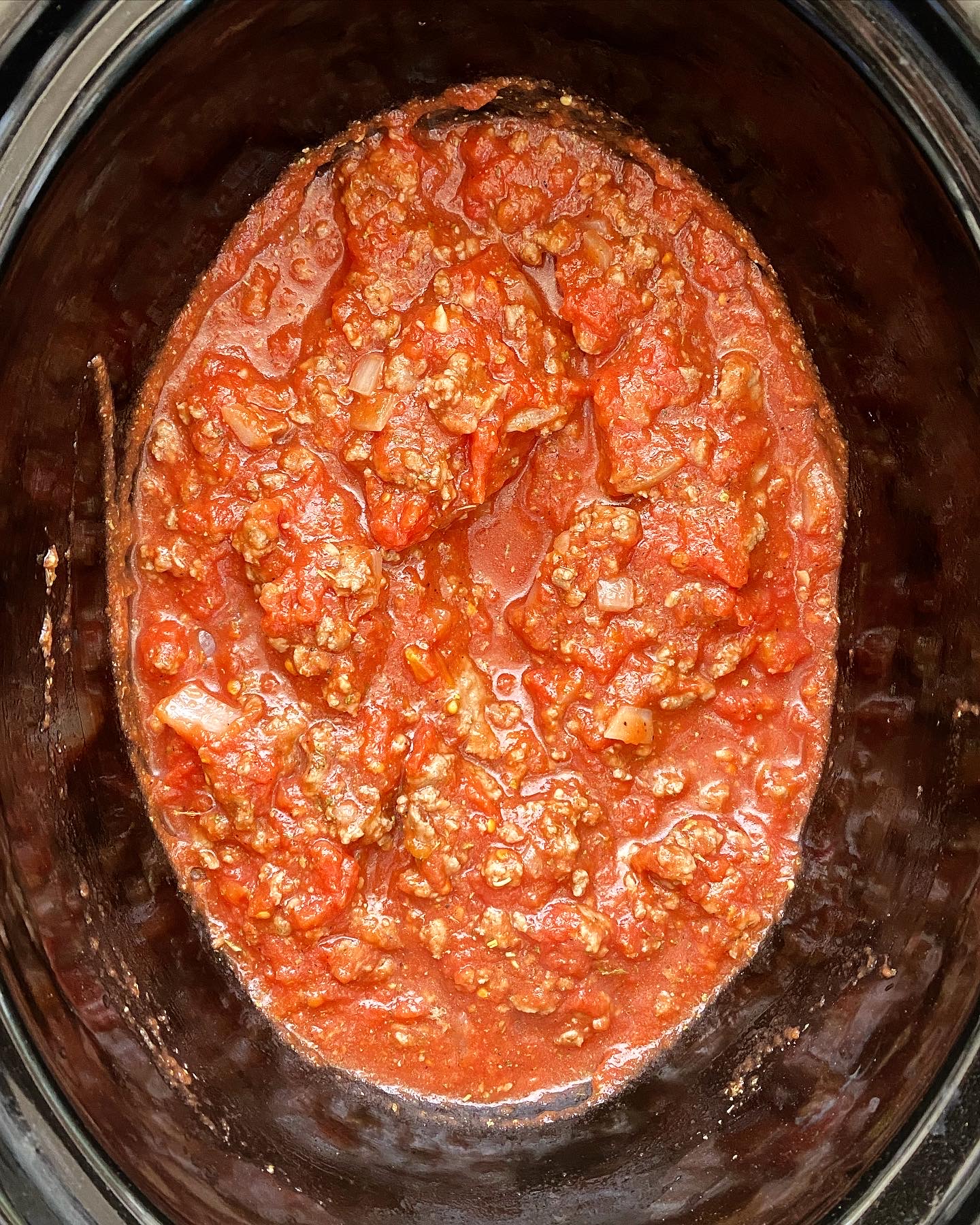 overhead shot of meat sauce in a black slow cooker