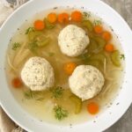 overhead shot of matzo ball soup in a white bowl
