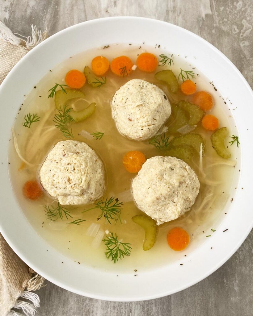 overhead shot of matzo ball soup in a white bowl
