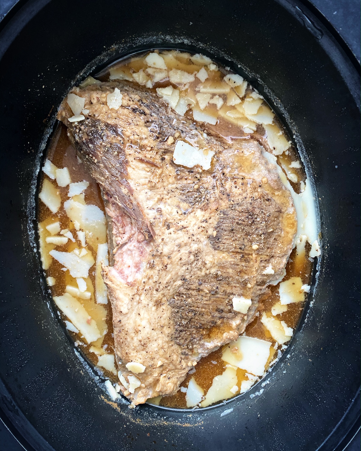 cold, cooked brisket in the slow cooker with hardened fat around the edges