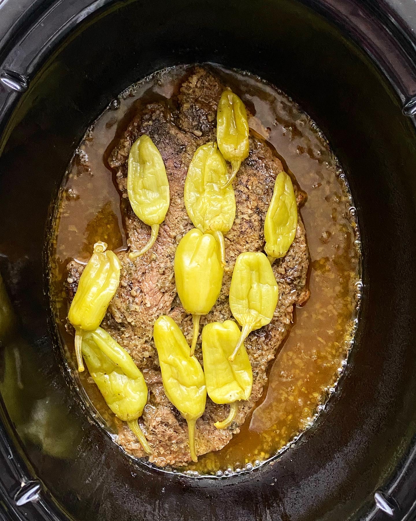 overhead shot of cooked Mississippi roast in a black slow cooker