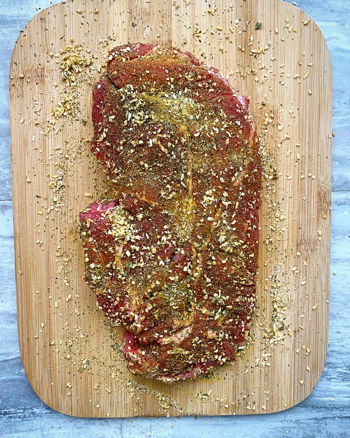 overhead shot of seasoned beef roast in a wooden cutting board