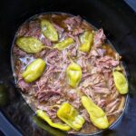 overhead shot of cooked Mississippi beef in a black slow cooker