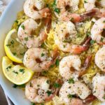spaghetti squash shrimp scampi on a white plate with lemon slices