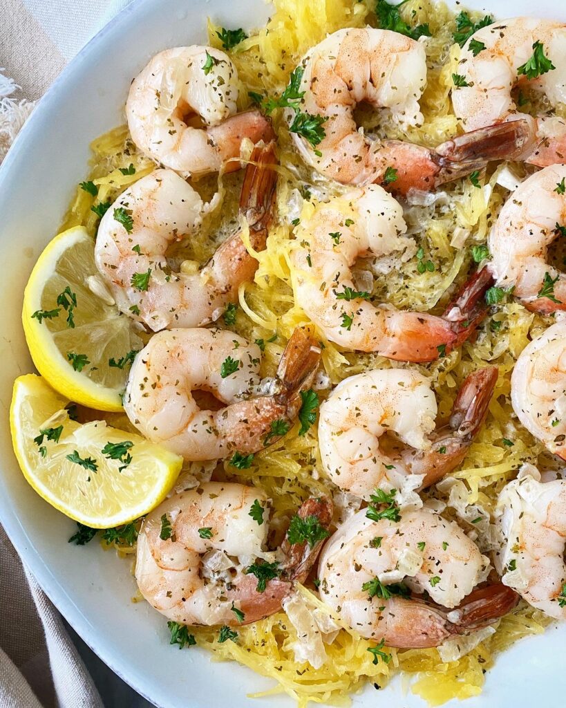 spaghetti squash shrimp scampi on a white plate with lemon slices