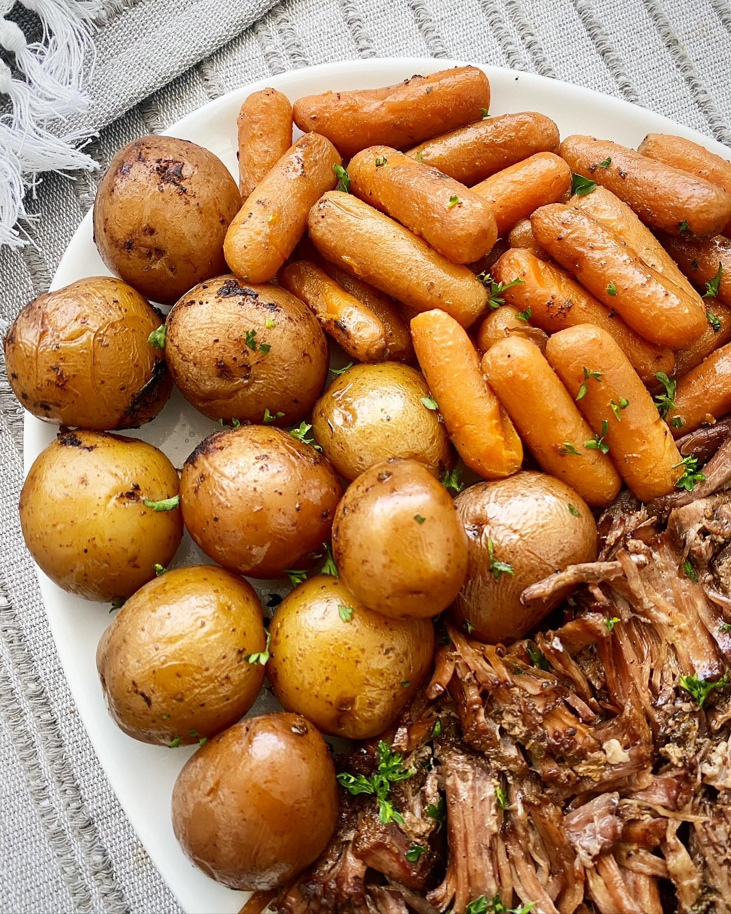 close up shot of cooked potatoes and carrots on a white platter 