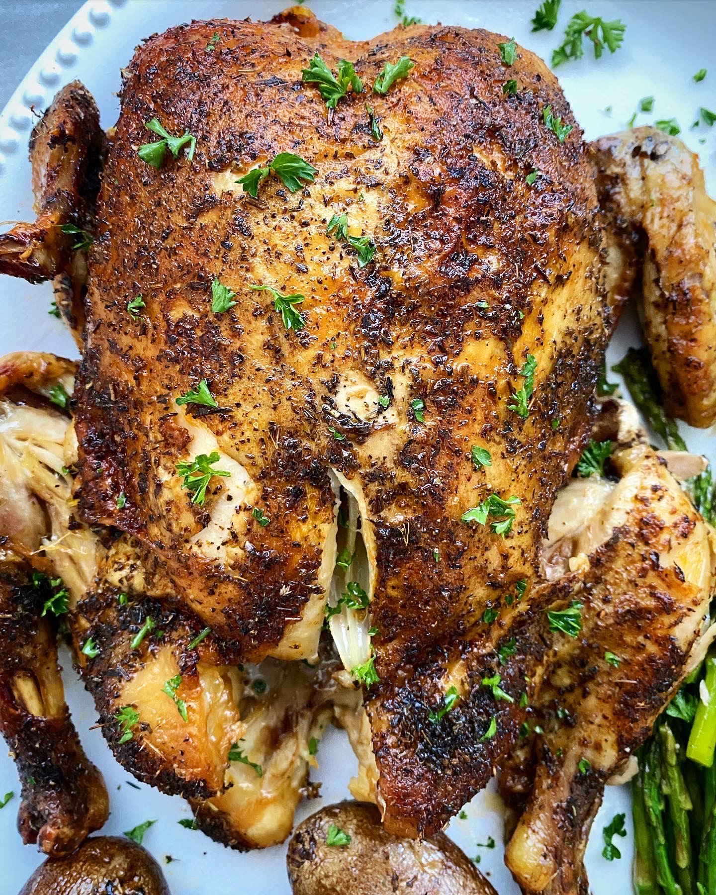 close up shot of cooked whole chicken on a white platter