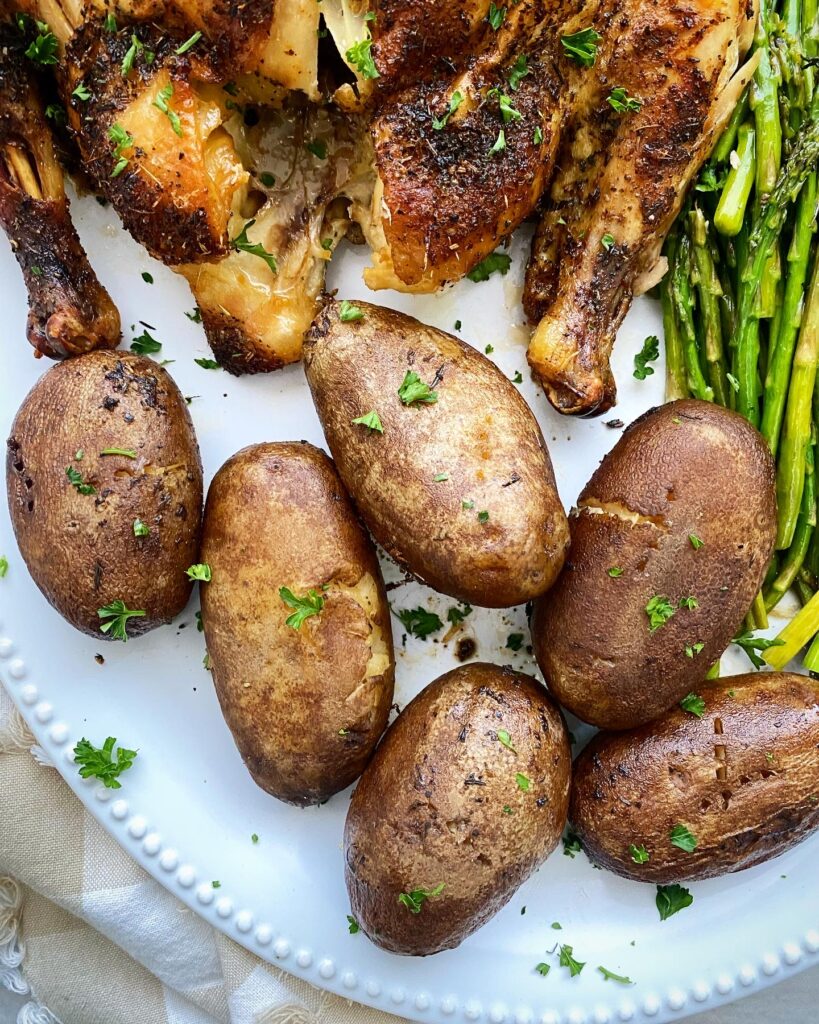 close up shot of 6 cooked potatoes on a white platter