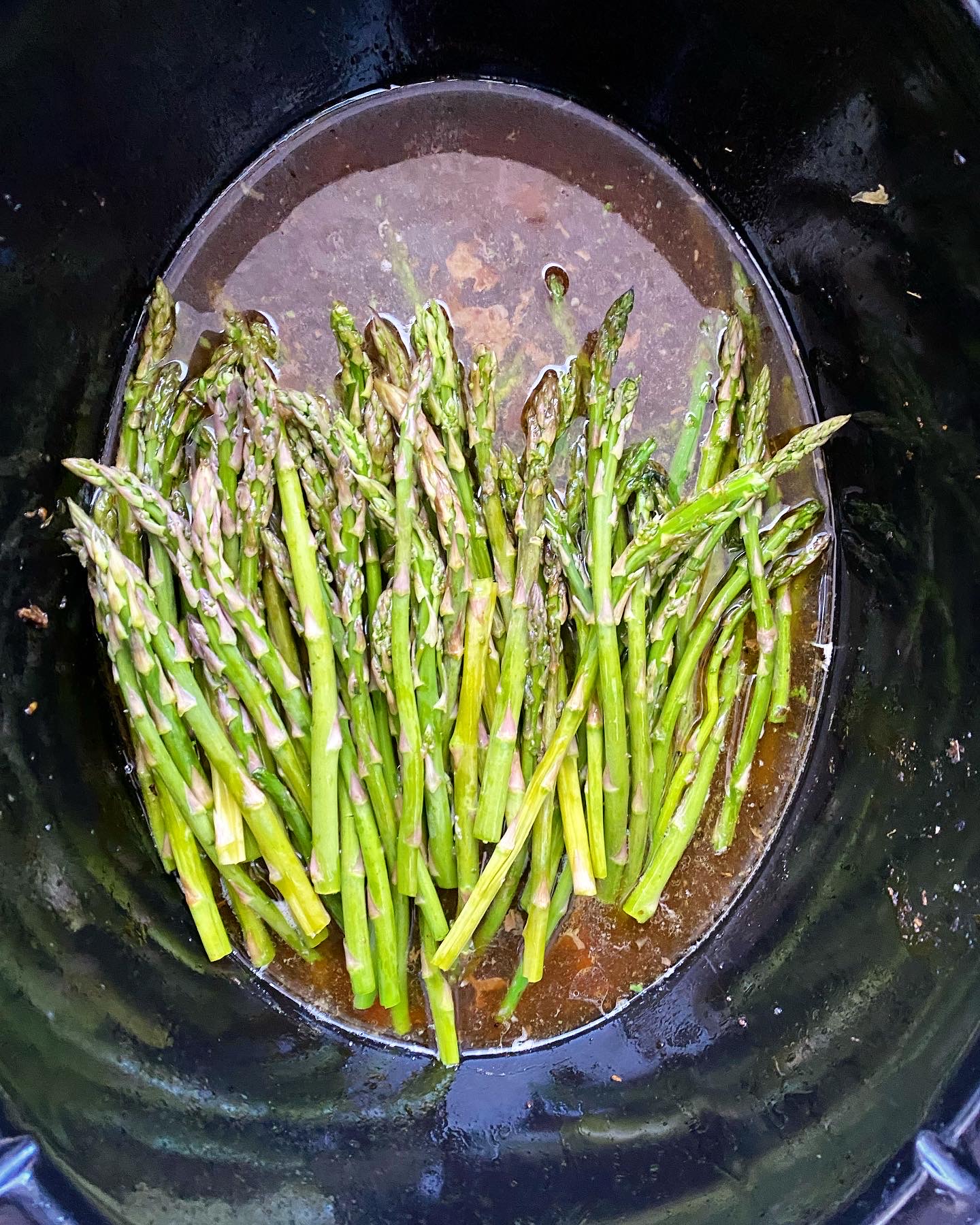 overhead shot of asparagus in a black slow cooker