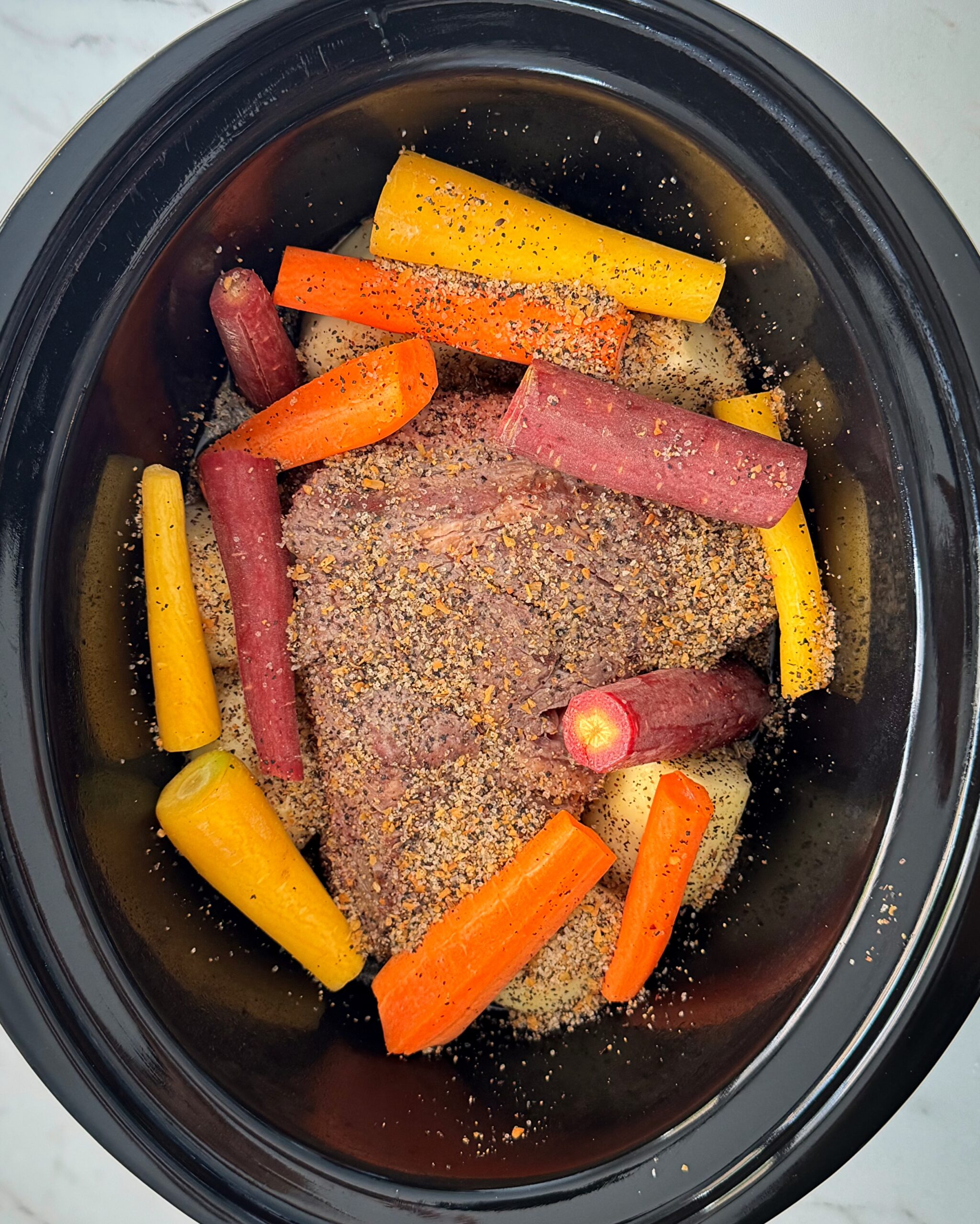 overhead shot of uncooked 5-Ingredient Pot Roast in a black slow cooker
