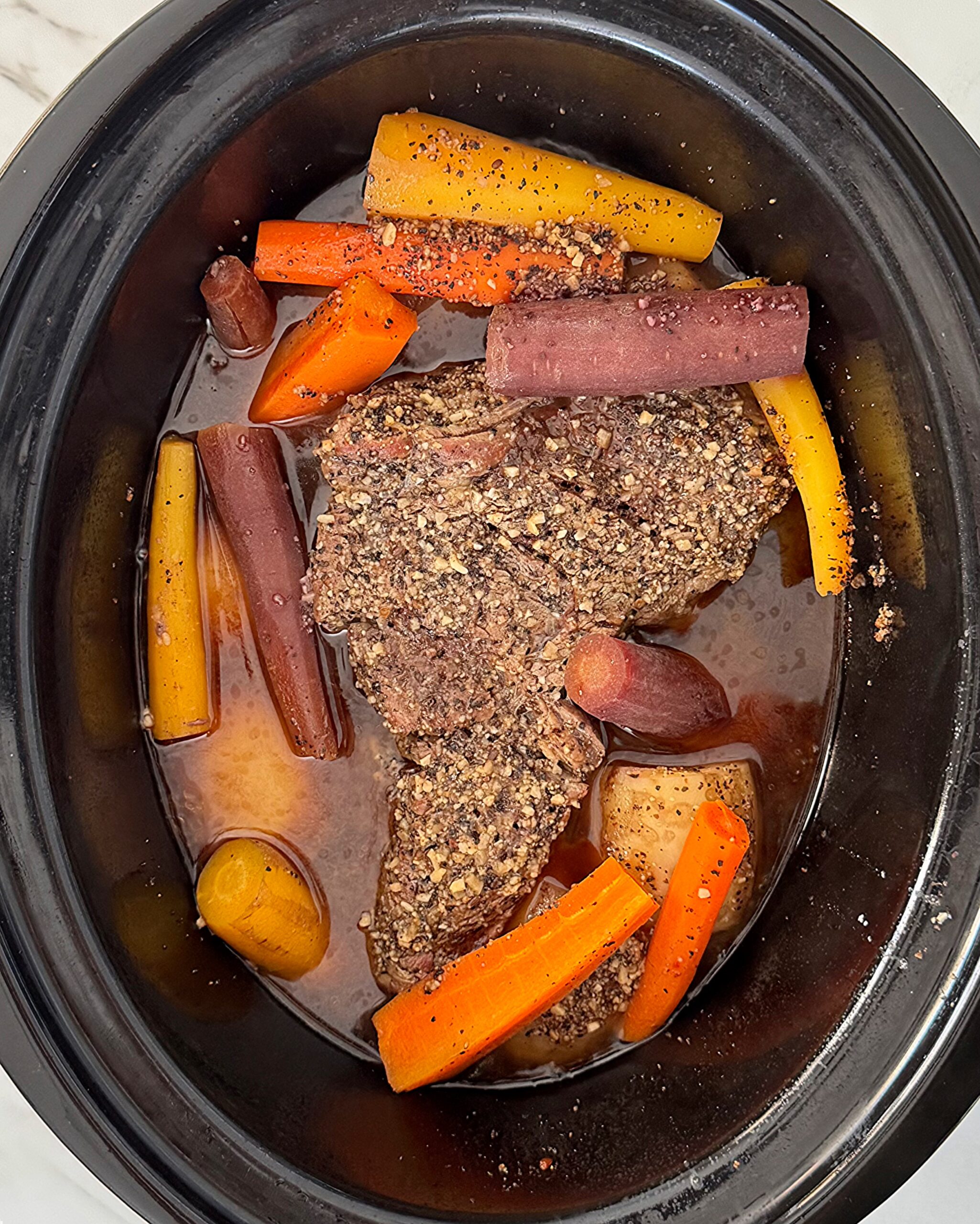 overhead shot of cooked 5-Ingredient Pot Roast in a black slow cooker