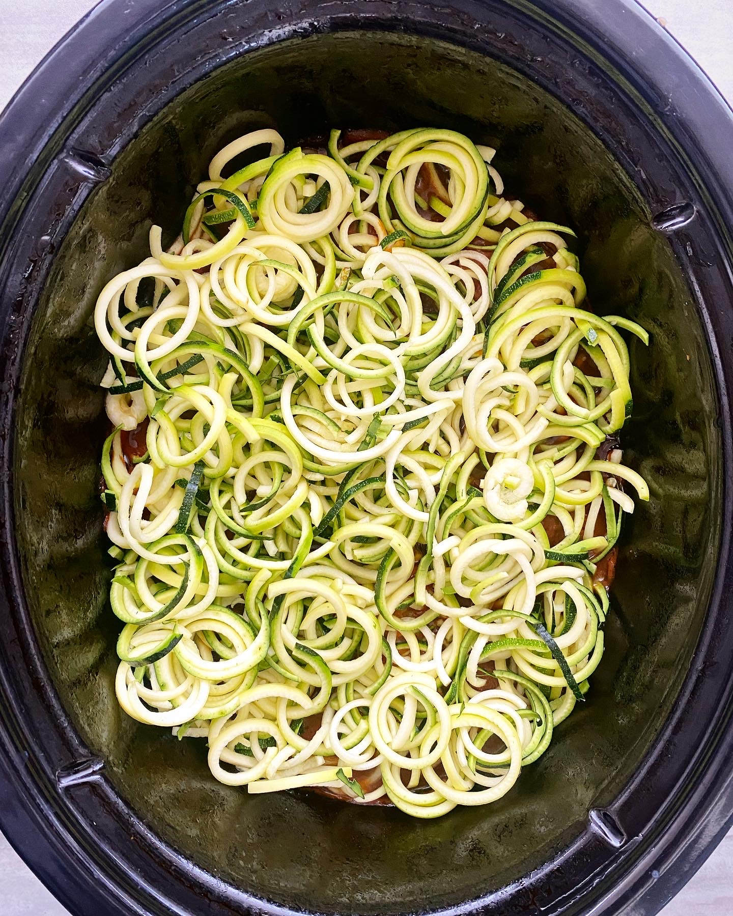 overhead shot of zucchini noodles in a black slow cooker