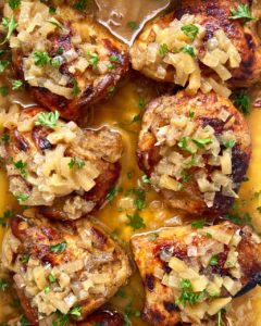 close up shot of cooked chicken with apples and honey in a white baking dish