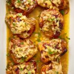 overhead shot of cooked chicken with apples and honey in a white baking dish